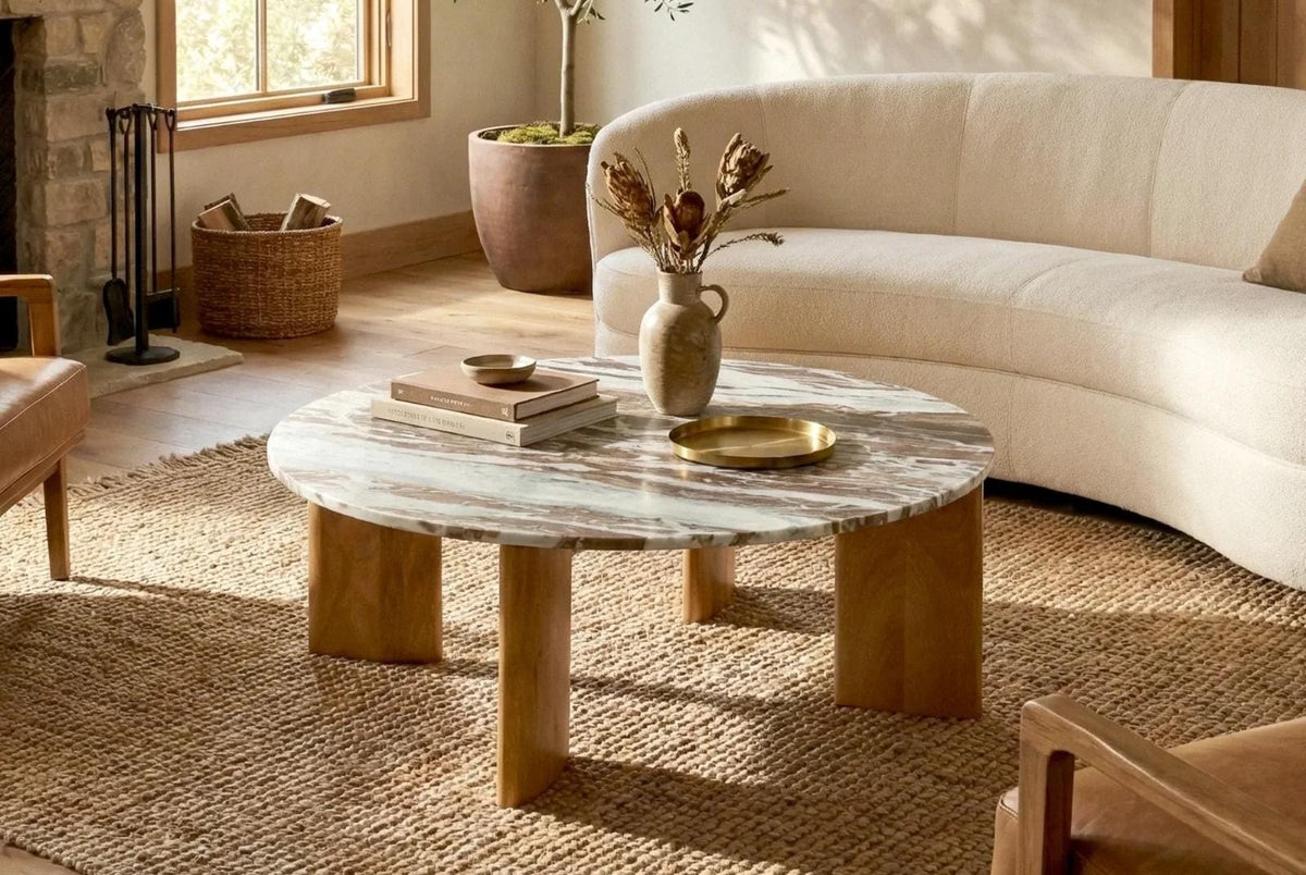 Solara marble coffee table with wooden supports paired with a curved cream sofa